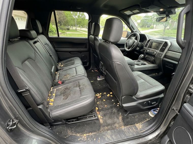 The same interior before, crumbs across the seats and stains ground into the carpet